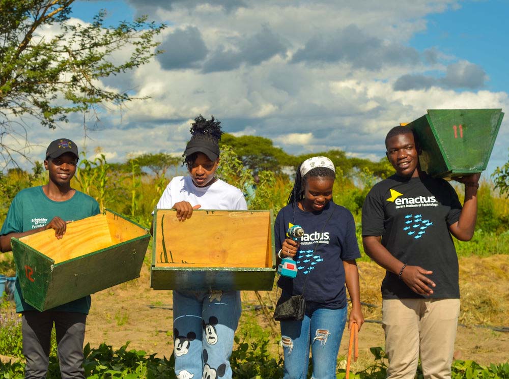 Four people stand outside holding wooden boxes