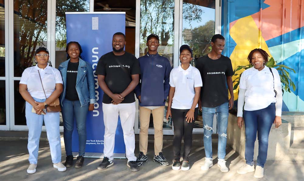 Seven people from the Zimbabwe Chapter and uncommon.org stand together and smile 